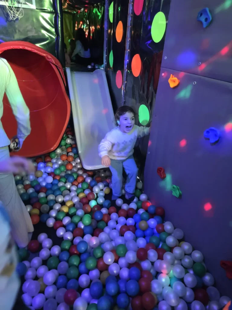 Child playing in the ball pit inside the Essex Soft Play Bus with colourful slide and soft play climbing wall.