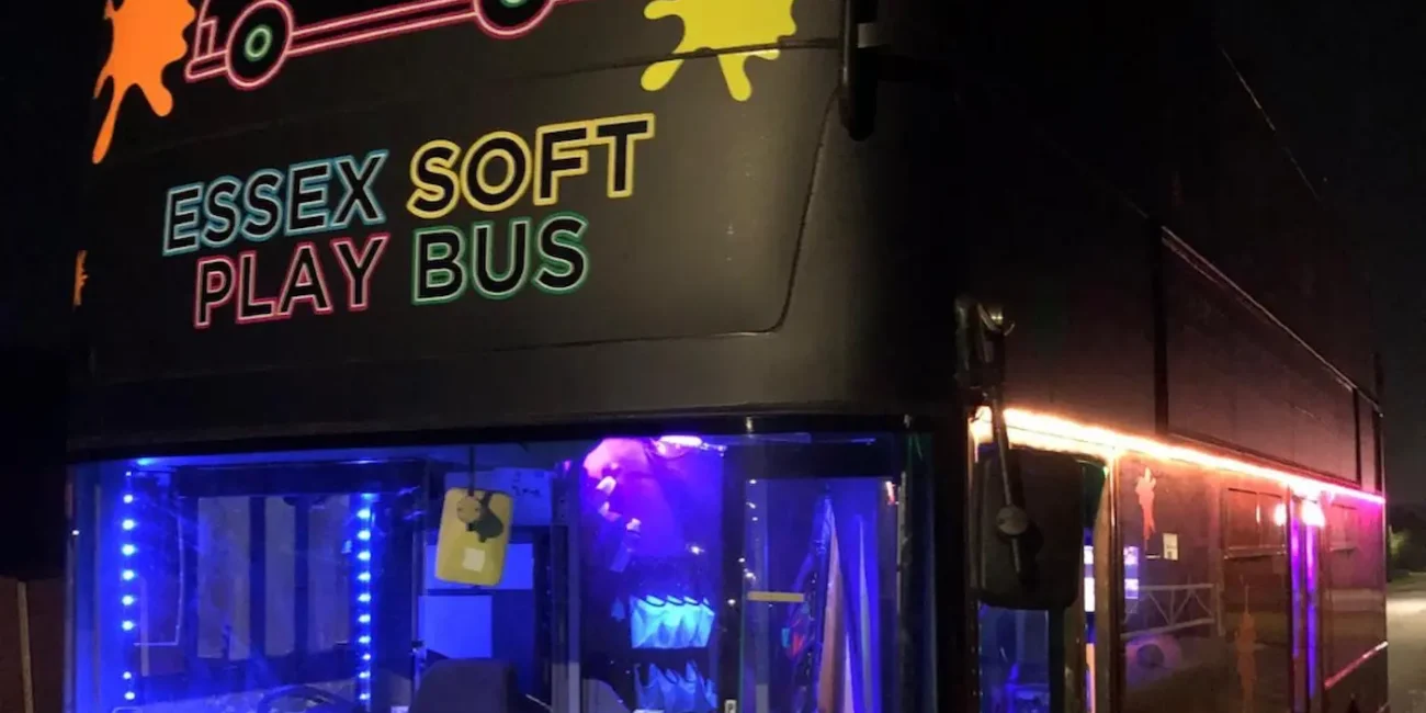 The Essex Soft Play Bus double decker soft play party bus illuminated at night outside a children's birthday party in Essex