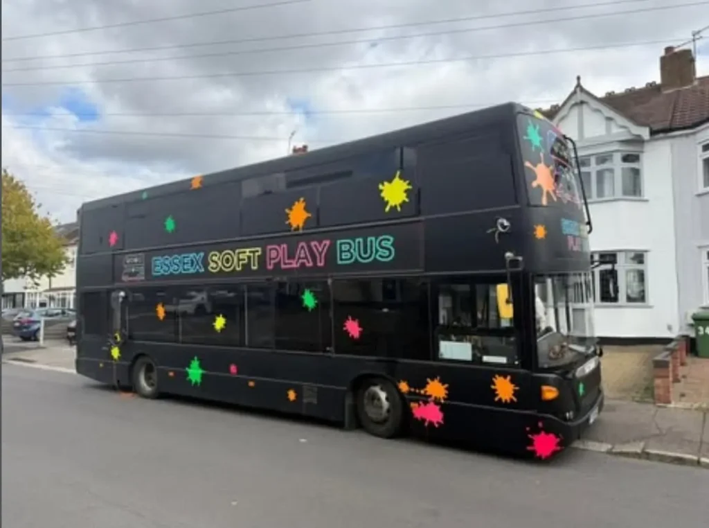 The Essex Soft Play Bus double decker children's soft play party bus lit up at night outside a birthday party in Essex