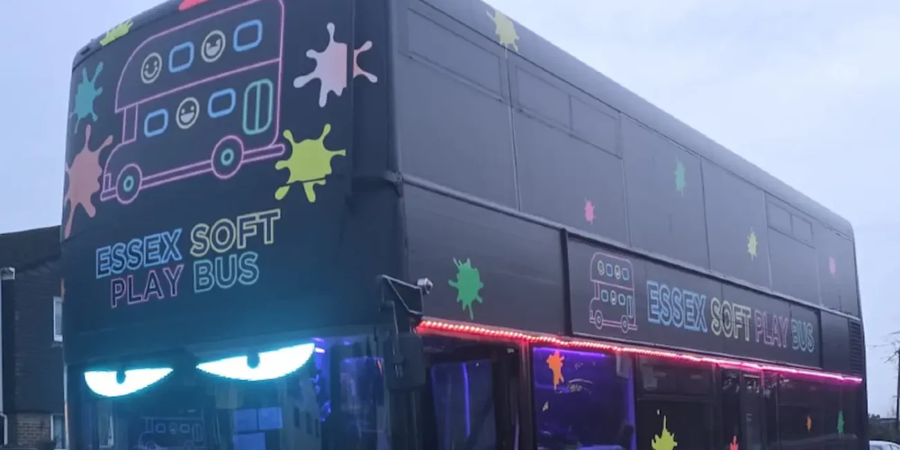 Rear and side view of the Essex Soft Play Bus double decker children's soft play party bus with colourful paint splash graphics in Essex