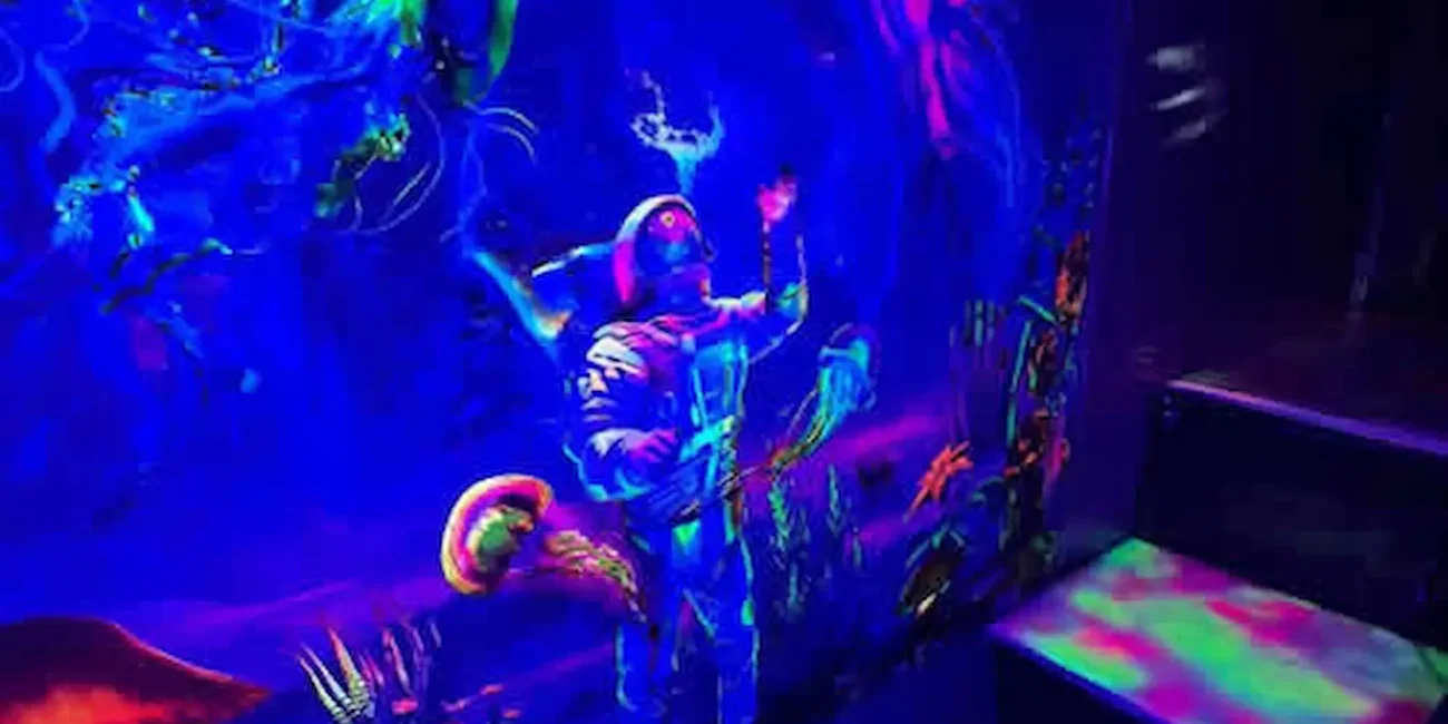 Neon themed climbing play area inside the Essex Soft Play Bus with colourful underwater wall artwork.