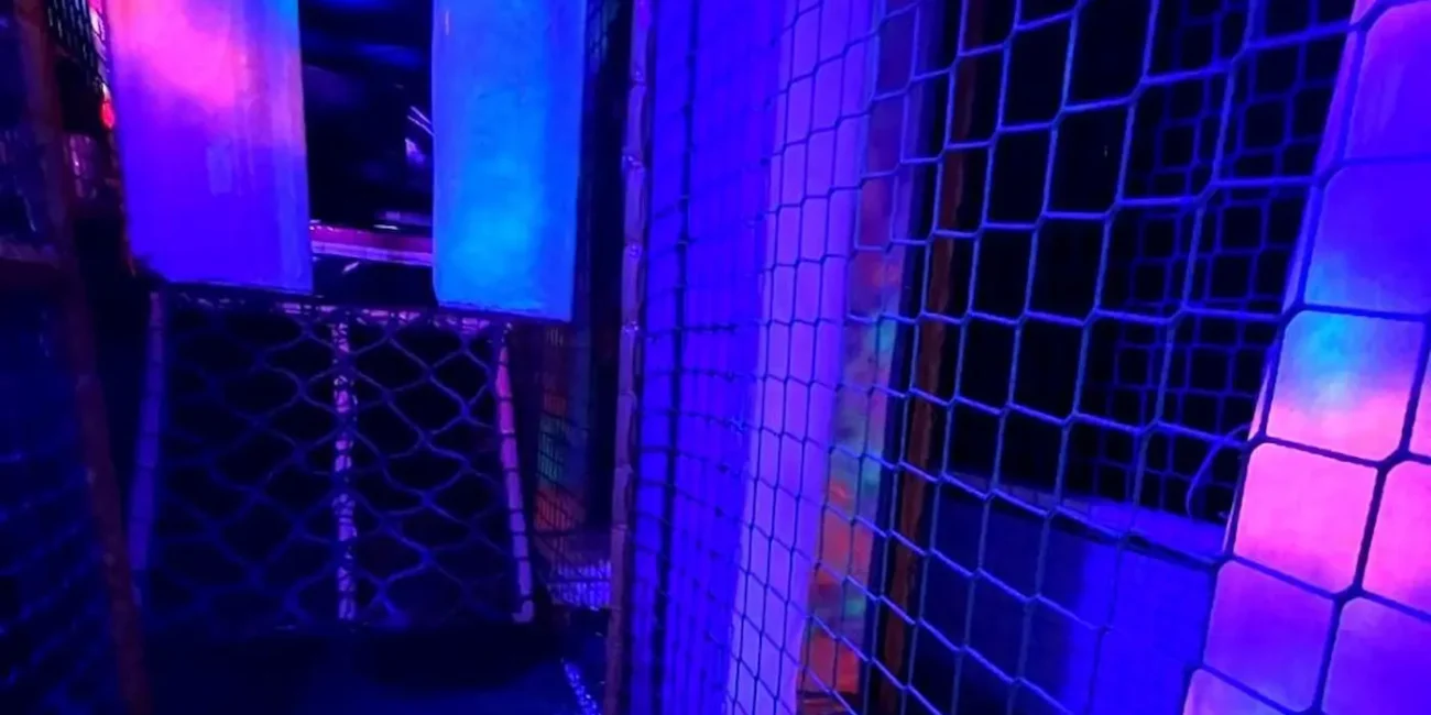 Neon soft play climbing frame and tunnel area inside the Essex Soft Play Bus with colourful UV lighting and indoor play equipment.