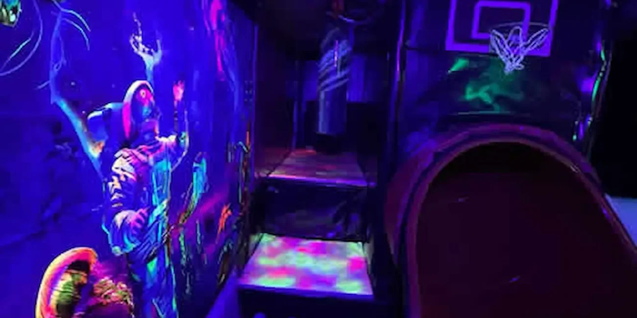 Neon soft play interior inside the Essex Soft Play Bus featuring colourful UV lighting, play tunnel and basketball hoop for children’s parties in Essex.