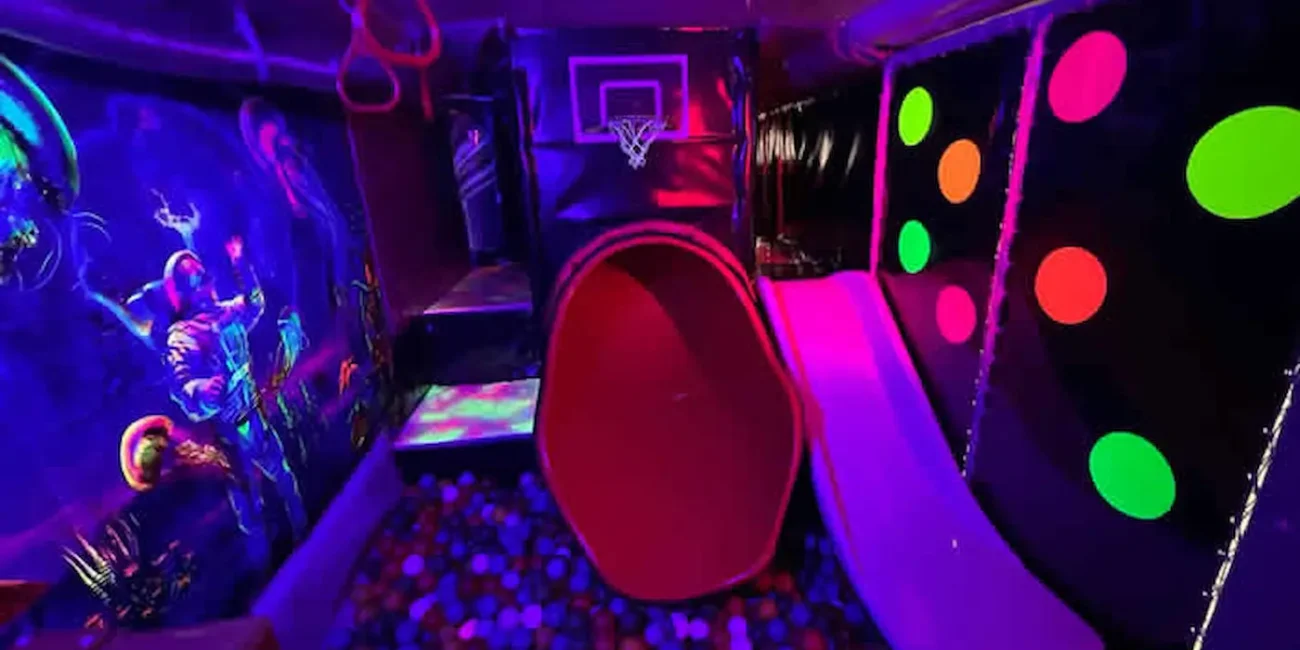 Children’s soft play tunnel and ball pit inside the Essex Soft Play Bus with colourful neon lighting and indoor play equipment.