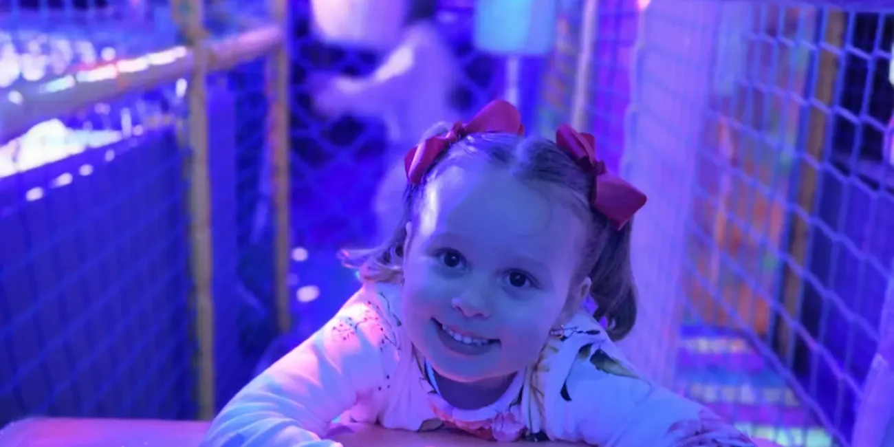 Child crawling through the neon soft play tunnel inside the Essex Soft Play Bus.
