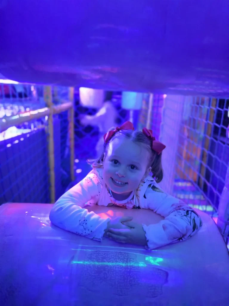 Child crawling through the neon soft play tunnel inside the Essex Soft Play Bus.